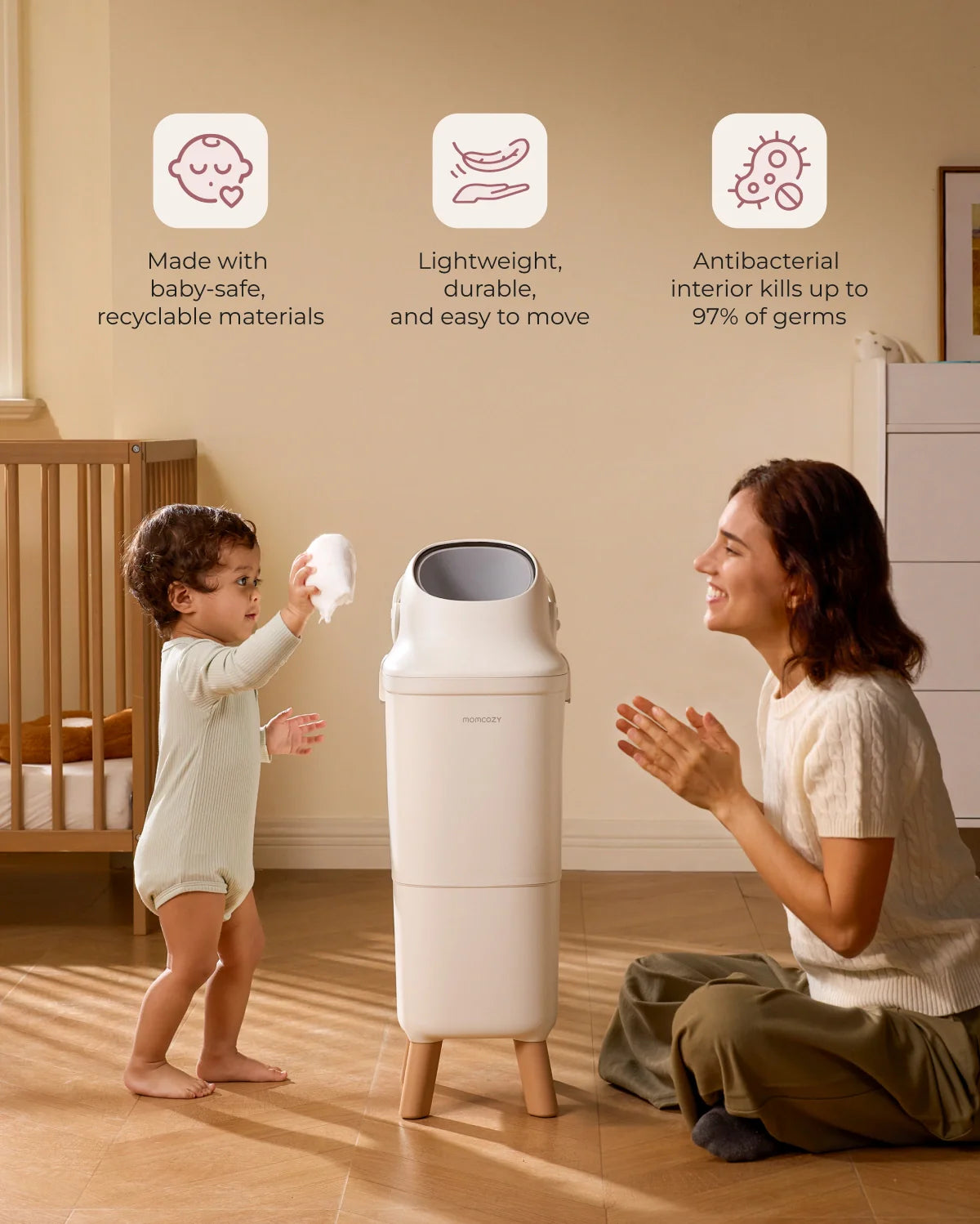 Momcozy Triple-Seal diaper pail in white with wooden legs, shown in nursery with parent and baby